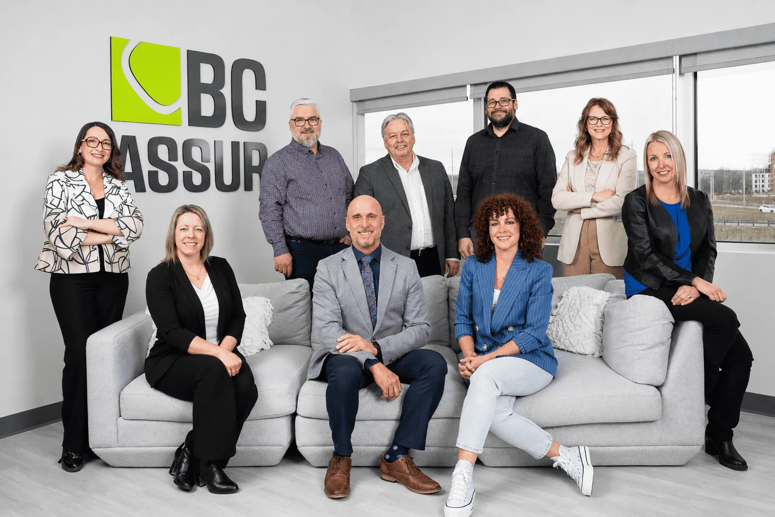Équipe de direction de BC Assur réunie devant le logo de l'entreprise