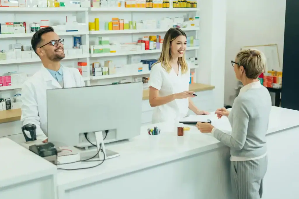 Pharmacienne et employée servant une cliente au comptoir, rayons de médicaments à l'arrière-plan