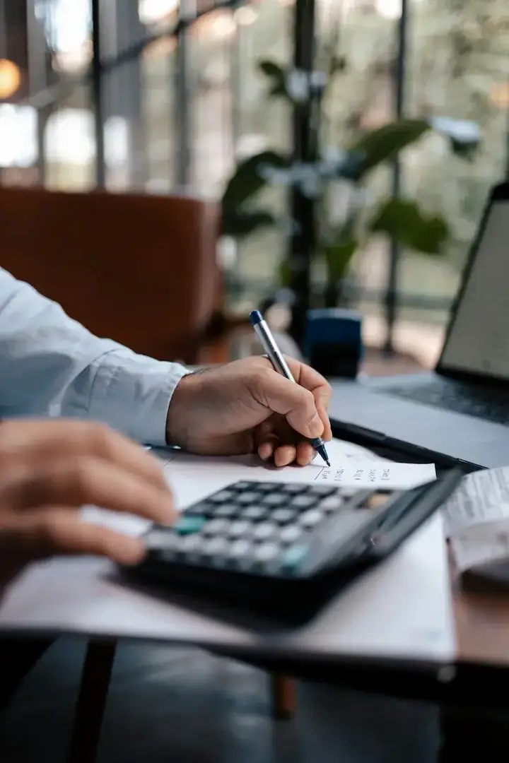 Dirigeant qui calcule ses coûts au stylo et à la calculatrice pour réduire la prime d'assurance entreprise