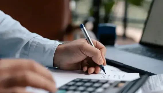 Dirigeant qui calcule ses coûts au stylo et à la calculatrice pour réduire la prime d'assurance entreprise