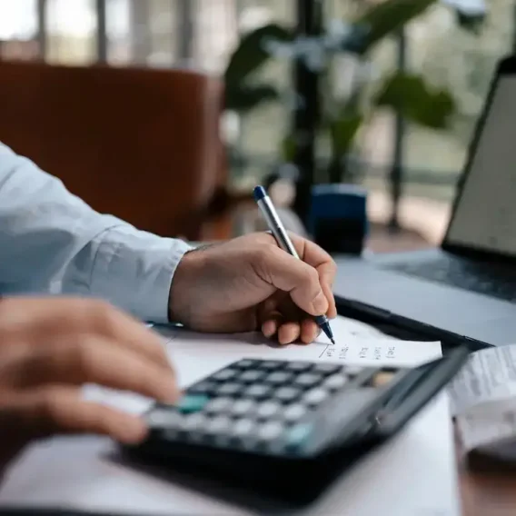 Dirigeant qui calcule ses coûts au stylo et à la calculatrice pour réduire la prime d'assurance entreprise
