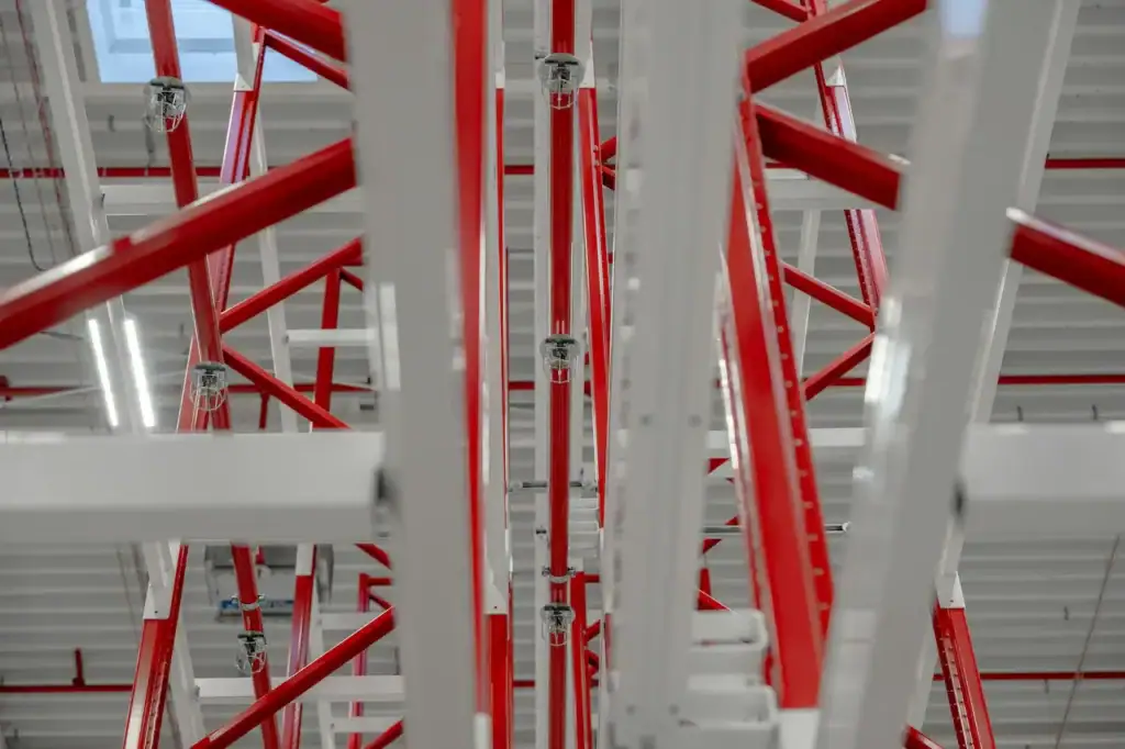 Réseau de gicleurs installés le long des rayonnages d'acier rouge et blanc d'un entrepôt