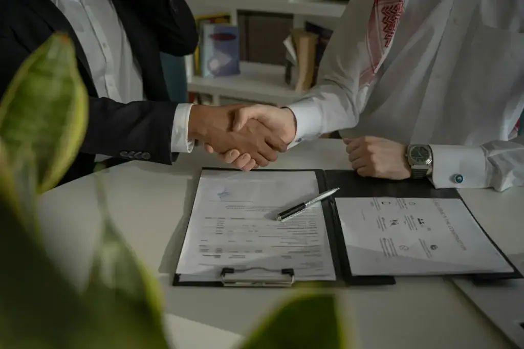 Poignée de main au-dessus d'un contrat signé, scellant un mandat avec un courtier en assurance pour entreprise