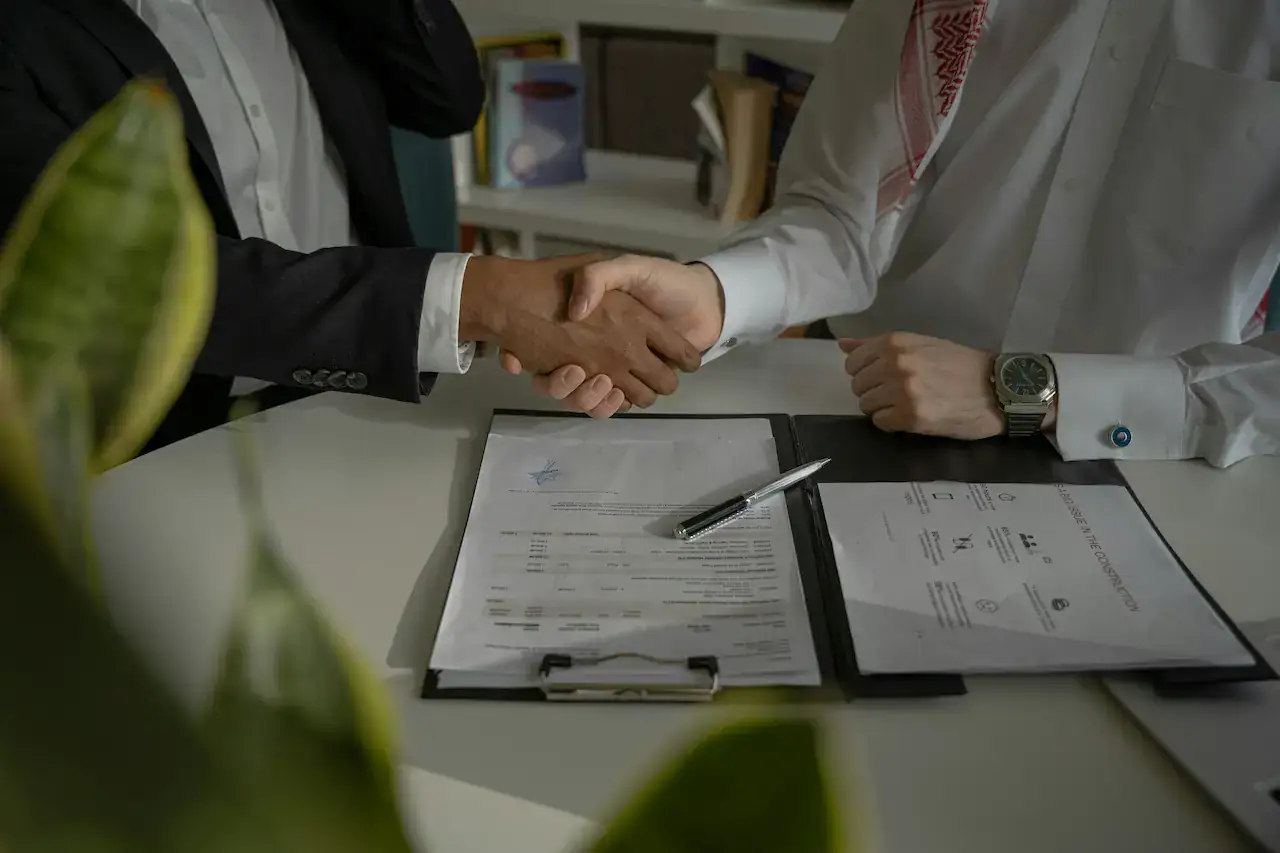 Poignée de main au-dessus d'un contrat signé, scellant un mandat avec un courtier en assurance pour entreprise